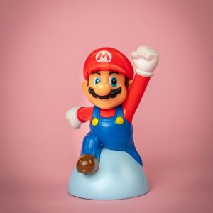 a mario figurine on a pink background