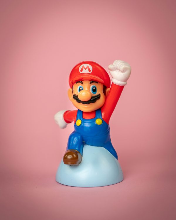 a mario figurine on a pink background