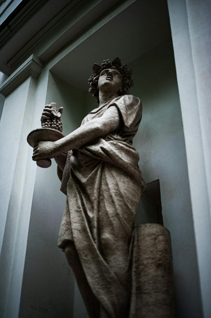 A statue of Dionysus holding a plate of grapes. 